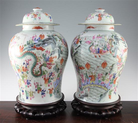 A pair of Chinese famille rose hundred boys baluster jars and covers, 19th century, 42cm, wood stands, one jar cracked